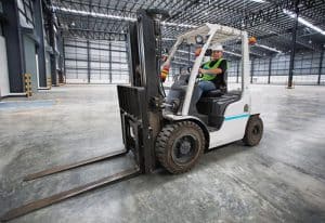 man driving a forklift through a warehouse in a factory